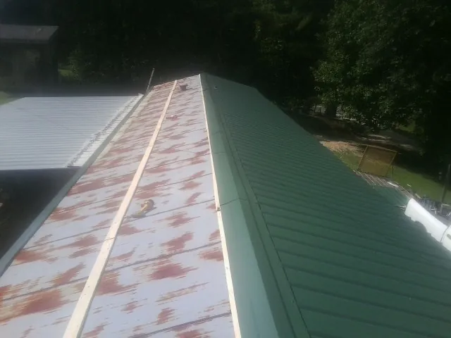 Old rusted panels beside newly installed green metal roofing — Wind Damage Roof Repair by Roofing Brothers in Stockton