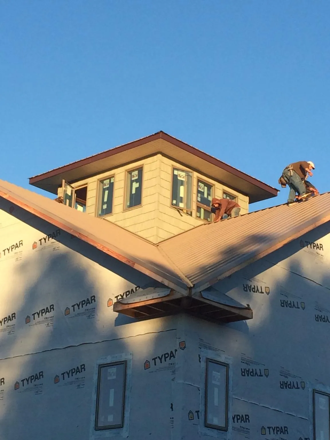 Roofers working around a rooftop cupola on a new metal roof at sunset — Roof Waterproofing in Stockton by Roofing Brothers